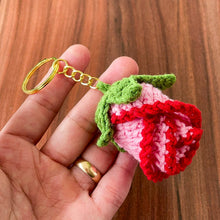 Two crochet rose keychains with pink and red petals and green leaves, handmade with yarn, attached to gold key rings. The roses have intricate detailing and a realistic flower shape, ideal as decorative accessories or gifts.