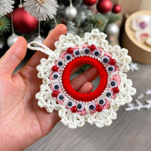 Handmade crochet Christmas wreath ornament with googly eyes and red beads, featuring a playful and festive design, perfect for holiday decor.