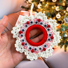 Handmade crochet Christmas wreath ornament with googly eyes and red beads, featuring a playful and festive design, perfect for holiday decor.