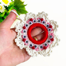 Handmade crochet Christmas wreath ornament with googly eyes and red beads, featuring a playful and festive design, perfect for holiday decor.