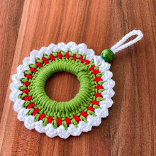 Handmade crochet Christmas wreath ornament with red, green, and white yarn, featuring a beaded loop for hanging. Perfect for holiday home decor or gift wrapping.