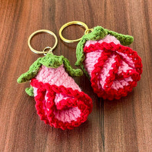 Two crochet rose keychains with pink and red petals and green leaves, handmade with yarn, attached to gold key rings. The roses have intricate detailing and a realistic flower shape, ideal as decorative accessories or gifts.