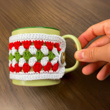 Handmade red, green, and white crochet mug cozy, Christmas-themed decorative cup cover, festive crochet cup sleeve for keeping drinks warm.
