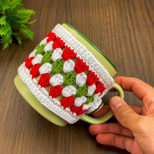 Handmade red, green, and white crochet mug cozy, Christmas-themed decorative cup cover, festive crochet cup sleeve for keeping drinks warm.