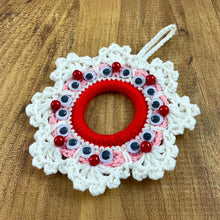 Handmade crochet Christmas wreath ornament with googly eyes and red beads, featuring a playful and festive design, perfect for holiday decor.