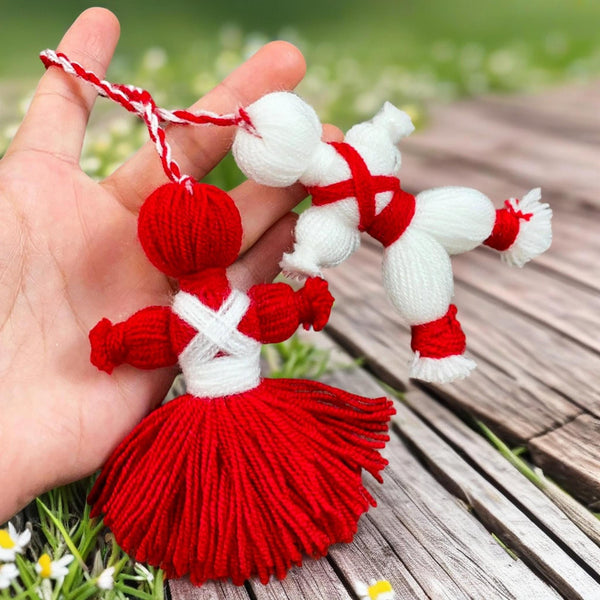 Traditional Bulgarian Martenitsa yarn dolls, Pizho and Penda, made from red and white yarn for Baba Marta Day celebrations.