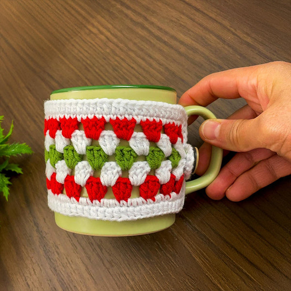 Handmade red, green, and white crochet mug cozy, Christmas-themed decorative cup cover, festive crochet cup sleeve for keeping drinks warm.