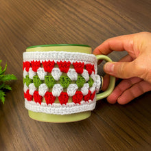 Handmade red, green, and white crochet mug cozy, Christmas-themed decorative cup cover, festive crochet cup sleeve for keeping drinks warm.