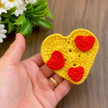 Handmade crochet heart motif featuring a large yellow base adorned with small red hearts, perfect for adding a touch of warmth and love to any craft project